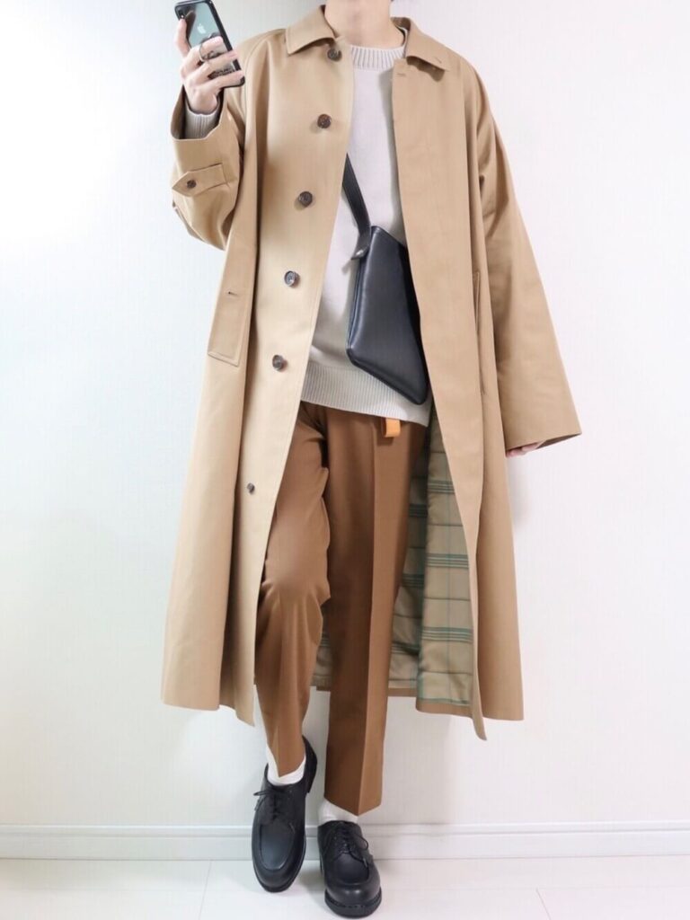 ベージュのステンカラーコート×ブラウンのスラックス×黒のブーツ×黒のショルダーバッグ
